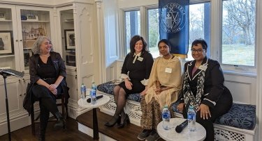 Mercy College moderator and panelists seated on stage before the event begins