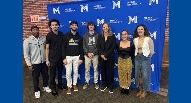 Students standing in front of step and repeat with guest speaker Sarah Jones-Maturo