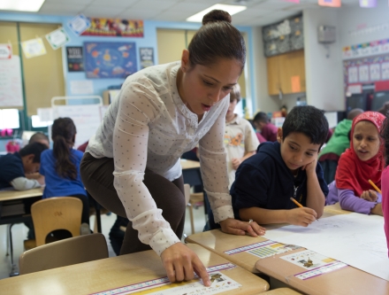 Kindergarten teacher helping students.