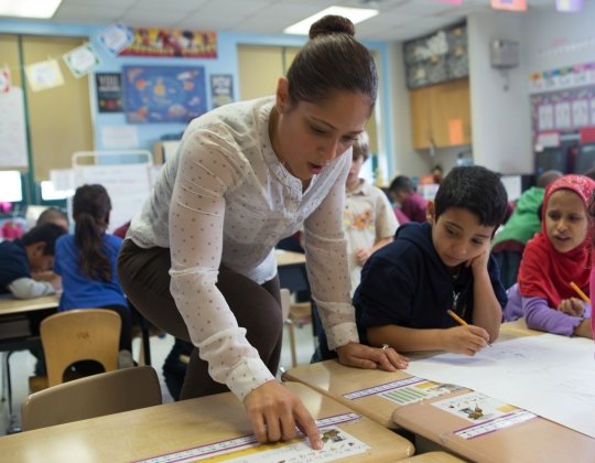 Kindergarten teacher helping students.